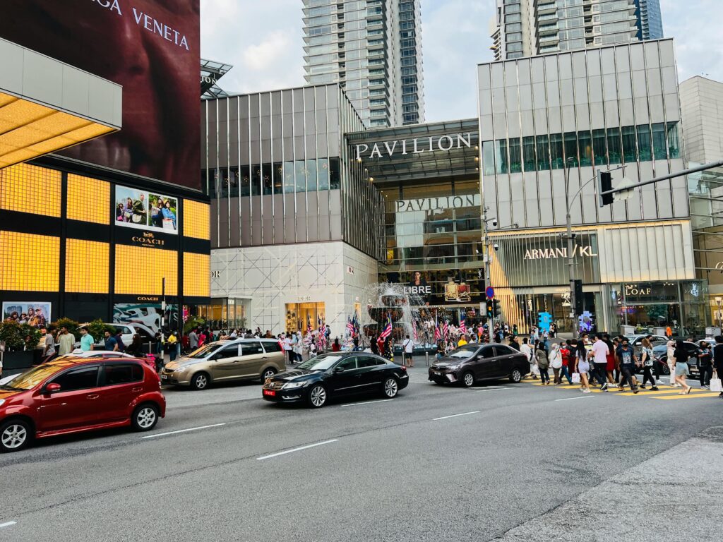Vibrant street view of Pavilion Kuala Lumpur, showcasing urban life with cars and pedestrians.