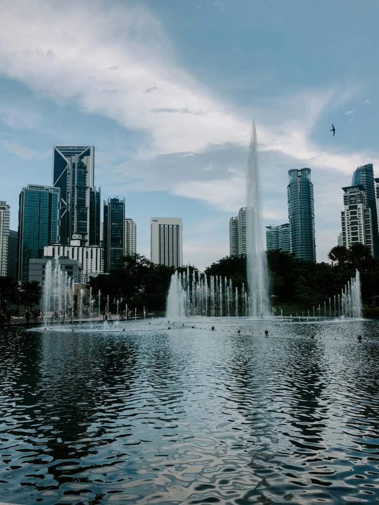 Picturesque scenery of contemporary city with skyscrapers with glass mirrored windows near fountain in daylight